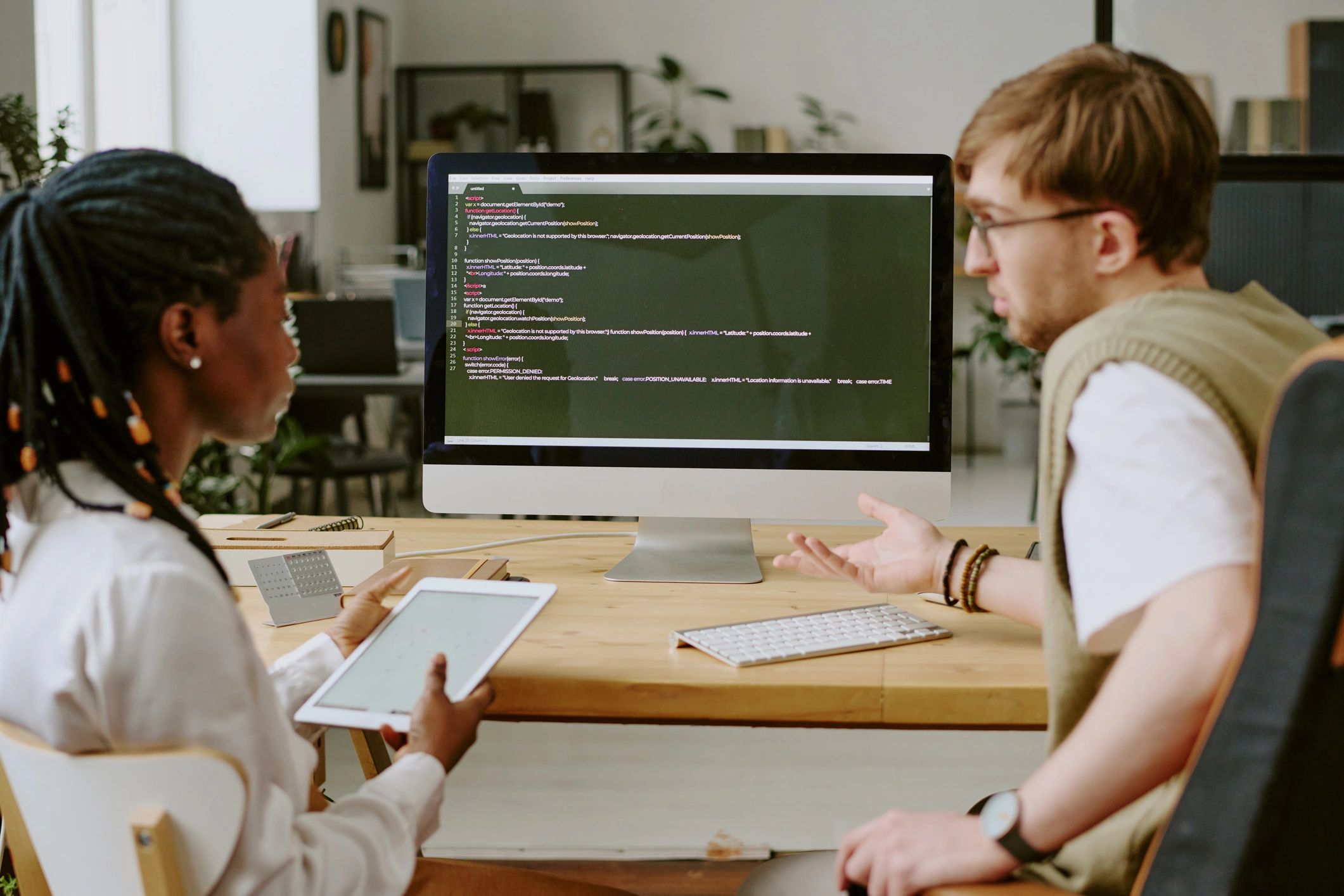 Developers discussing code in front of a large monitor